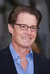 A headshot of a smiling man in glasses