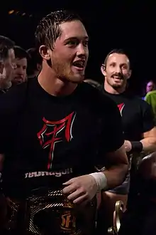 Bobby Fish and Kyle O'Reilly, two black-haired Caucasian men in black reDRagon T-shirts with the ROH World Tag Team Championship belts