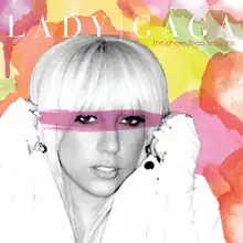 Lady Gaga's face, in black and white, against a colorful background of pink, yellow, red and green shapes.