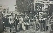 The Duke and Duchess of Saxe-Coburg and Gotha with two other men walking towards an outdoor display of agricultural equipment