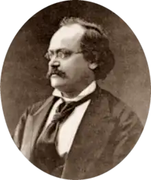 photograph of middle-aged white man with receding dark hair, spectacles and moustache, in semi-profile, facing right