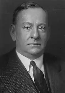 Face portrait of clean-shaven man in a suit in a black-and-white photo.