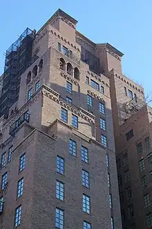 The brick facade of the upper stories, which includes rectangular windows. There are arched corbel tables beneath the setbacks.