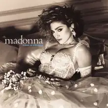 A sepia-toned image of Madonna in a wedding dress, with a belt with "Boy Toy" inscribed on its buckle.