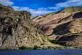 Steep rocky cliff and sandy hillside rising from a lake