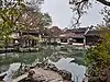 A pavilion on an island in the pond connected to two grape trellise