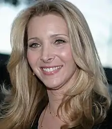 A woman with blonde hair, smiling and looking in a left-to-right direction.