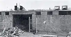 A pile of metal cans outside a fire-damaged brick building