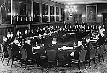 London Conference, St. James' Palace, February 1939. Palestinian delegates (foreground), Left to right: Fu'ad Saba, Yaqub Al-Ghussein, Musa Alami, Amin Tamimi, Jamal Al-Husseini, Awni Abdul Hadi, George Antonius, and Alfred Roch. Facing the Palestinians are the British, with Sir Neville Chamberlain presiding. To his right is Lord Halifax, and to his left, Malcolm MacDonald.