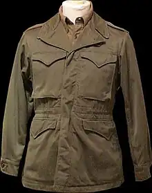 An olive drab M-1943 field jacket, worn by US soldiers during World War II and the Korean War.