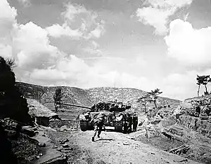 A tank drives up a rocky ridge