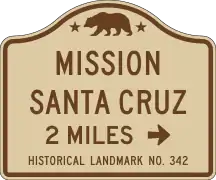 The California Manual on Uniform Traffic Control Devices specifies a standard road sign guiding motorists to California Historical Landmarks, such as Mission Santa Cruz.