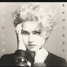 Madonna's image with her right hand placed on her right cheek and with the left hand, she holds on to a number of chains wound on her neck.