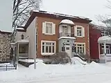 A small brick building with a side porch during winter