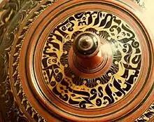 Top of a malaafaiy (wooden cover for food items) with Arabic writing. Lacquered wood made in Thulhaadhoo Island, 1985.