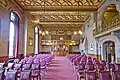 The original Council Chamber, Manchester Town Hall, the painted frieze around the top of walls has tendrils of cotton plants and contains shields with the coat of arms of the surrounding cotton-weaving towns. Note the gallery on the right with wrought-iron balustrade was for members of the public, the recess beneath housed the press, and the stone hooded fireplace, the Mayor's chair used to stand beneath the wooden canopy on the end wall, this was accessible from the Mayor's suite located on the other side of the wall, the wooden gallery above the screen was for the recording clerks