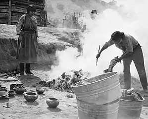 María and Julián Martinez pit firing blackware pottery at  P'ohwhóge Owingeh (San Ildefonso Pueblo), New Mexico (c.1920)