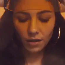 A color photograph of Marina Diamandis wearing a translucent orange visor.