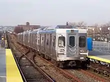 A silver subway train leaving a station