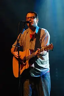 Matthew Good standing onstage, holding guitar, and singing into microphone