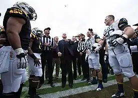 Man flips a cookie to determine which team will kick off.