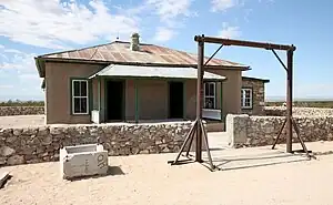 Single-storey building in a desert landscape with a corrugated metal roof and a veranda