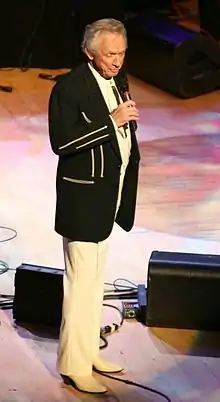 Country music singer Mel Tillis is performing on a stage.