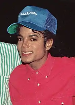 A man wearing blue cap and red shirt is smiling