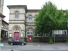 Two storey building, partially obscured by trees