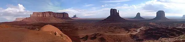 Panorama of rock formations at Monument Valley in Arizona. A red, barren, desert landscape with several mesas and gigantic, unusual rock formations.