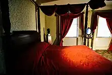 A bedroom, which belonged to Aaron Burr, with a red bedspread