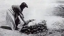 black-and-white photograph of a woman leaning over a fire