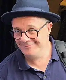 Photograph of a man wearing glasses and a hat