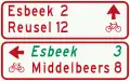 K8: Signposts (multiple) for cyclists and moped riders showing intermediary destinations and indicating an alternative route (in italics) to one of the destinations