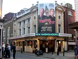 Exterior view of theatre with large poster advertising the current attraction.