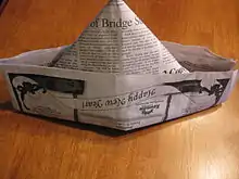 A newspaper folded into a triangular hat.