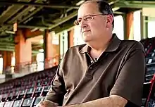 A man sitting in the stands at a baseball stadium