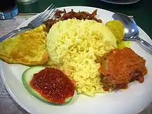 A dish of rice surrounded by various condiments