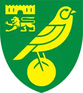 Badge of Norwich City: a green shield with yellow emblems. A bird (canary) on top of a ball as the main image, and a castle above a lion passant guardant in the top left quarter.