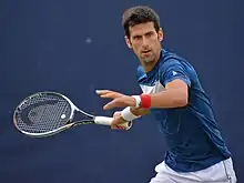 Tennis player Novak Djokovic preparing to hit a shot.