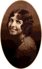 A studio photograph of a young woman looking over her shoulder.