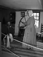 A woman demonstrates spinning wool into yarn