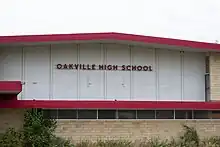 On the side of a gymnasium, the sign reads "Oakville High School".