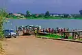 Bank of Oguta Lake showing human activities and rural dwellers. These include motorcyclists, loaded pontoon and automobile drivers engaged in movement of goods, services and people.