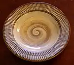 A plate with a spiral pattern in the middle and a stripe pattern along the rim.