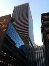 Ground-level view of a 38-story rectangular skyscraper with a tan facade and dark bluish windows