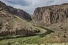 View over a river bend in a shrubby desert landscape framed by vertical cliffs