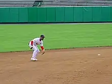 Player fielding a ground ball on a dirt infield