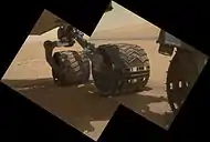 Wheels on the Curiosity rover. "Mount Sharp" is in the background (MAHLI, September 9, 2012).