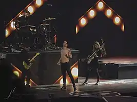 Panic! at the Disco at the Pepsi Center in 2018.From left to right: Kenneth Harris (guitar), Dan Pawlovich (drums), Brendon Urie (vocalist), and Nicole Row (bass)